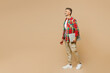 © ViDi Studio - Full body side view adult IT man he wear red shirt white t-shirt casual clothes hold closed laptop pc computer isolated on plain pastel light beige color background studio portrait. Lifestyle concept.