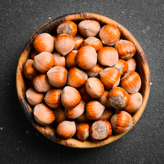 Wall Mural - Hazelnuts in a wooden bowl. Hazelnut nut health organic brown filbert autumn background concept. Close up.