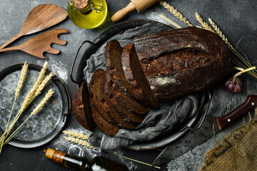 Wall Mural - Rye sourdough bread with flax cut on a board. Fresh bread on a black background. Top view.