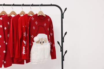 Wall Mural - Rack with different Christmas sweaters on white background, space for text