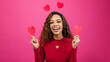 Cute multi-ethnic woman poses with paper hearts, symbol of love studio Valentine