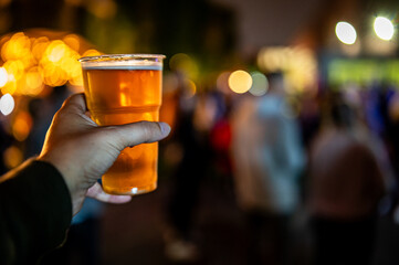 Wall Mural - plastic cup glass with beer in hand. Outdoor summer festival