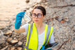 Top view of young Caucasian woman wearing eyeglasses research water test. Ecologist examines chemical sample flask. Concept of environmental pollution and ecology