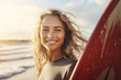 Portrait of a smiley young woman with a curly hairstyle carrying a colorful surfboard shot at the sunny day of beach vacation. Generative AI.