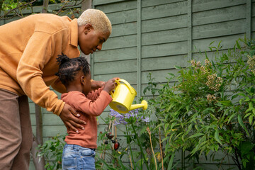 Wall Mural - Mother and daughter (2-3) watering plants in garden