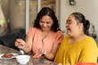 © Cultura Creative - Mother eating dinner with down syndrome daughter at home