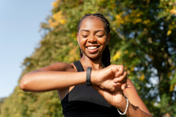 Wall Mural - Smiling young woman checking time after jogging