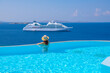 Tourist enjoying at the infinity pool with cruise view, Mykonos, Greece