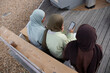 © Cultura Creative - Three Muslim women using smart phone while sitting on bench