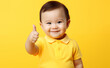 © Curioso.Photography - Asian toddler giving a thumbs up on yellow background.