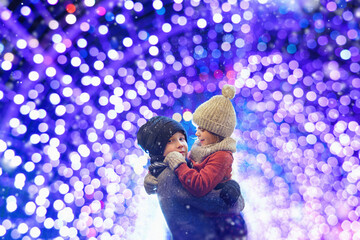 Wall Mural - Cute girl and boy enjoying the holidays at Christmas. Happy siblings play in the illuminated xmas city.