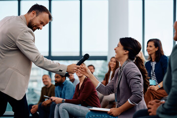 Happy presenter interacting with audience during business seminar in conference hall.