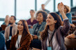 © Drazen - Happy entrepreneur raising her hand to answer question during business conference in convention center.