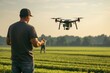 © evgenia_lo - Man using drone with the remote control on technological tablet, drone flying over green fields and filming it while being controlled by man