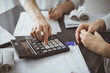 © rogerphoto - Woman accountant using a calculator and laptop computer while counting taxes for a client. Business audit and finance concepts
