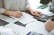 © rogerphoto - Woman accountant using a calculator and laptop computer while counting taxes with a client or a colleague. Business audit team, finance advisor