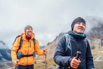 Wall Mural - caucasian and sherpa men backpackers with trekking poles together hiking and enjoying mera peak clim