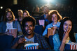 © Marko Geber - Young people sitting at the cinema watching a movie and eating popcorn