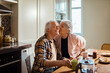 © Marko Geber - Senior woman kissing husband on cheek in kitchen