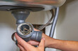 clogged sink pipe in hand,a plumber cleans a clogged siphon pipe of a sink in the kitchen