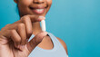 female hand holding white capsule on blue background close copy space medicine concept