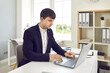 © Studio Romantic - Male office worker works on laptop with electronic documents while sitting in office. Smart concentrated man in jacket typing on keyboard, sending e-mail or filling out spreadsheets. Business concept.