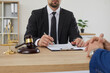 © Studio Romantic - Crop faceless unrecognizable male lawyer sitting at office table with gavel and scales of justice and asking his client to sign paper contract agreement. Law consultation, legal services concept