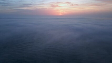 Wall Mural - Aerial view of a sunrise sea with a blanket of morning fog and morning sunbeams shining through