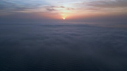 Wall Mural - Aerial view of a sunrise sea with a blanket of morning fog and morning sunbeams shining through