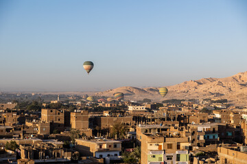 Wall Mural - hot air balloons floating over dusty desert villages in luxor egypt