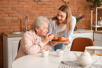 Sticker - Young woman with her grandmother eating buns in kitchen