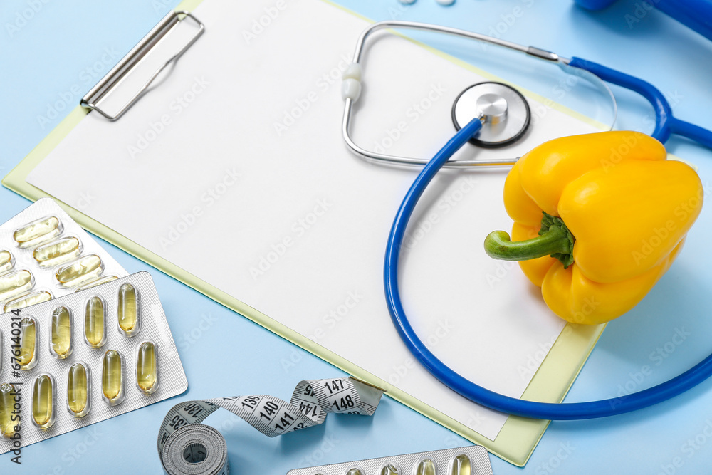 Composition with blank clipboard, pills, stethoscope and bell pepper on color background, closeup