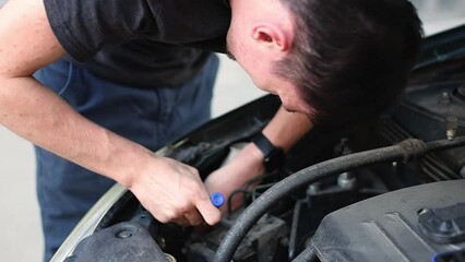 Wall Mural - A young guy unscrews a car headlight bulb with a screwdriver.