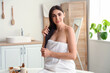 © Pixel-Shot - Beautiful young woman applying coconut oil onto her hair in bathroom