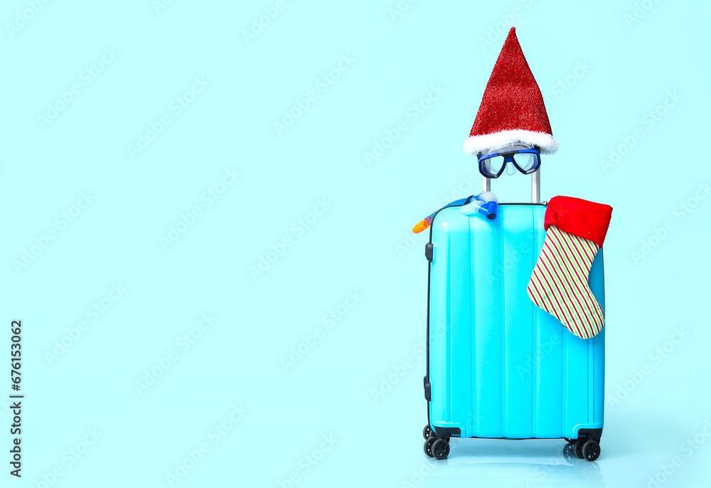 Suitcase with snorkeling mask, Santa hat and Christmas sock on color background