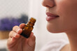 Woman with bottle of essential oil indoors, closeup