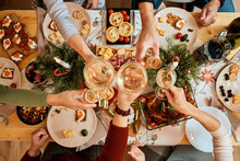 Top View Of A Christmas New Year's Eve Decorated Table,  Five Non-personalized People Eating At The Table, Passing Dishes To Each Other