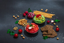 Various Hummus Dips, Fresh Vegetables And Herbs. Crispy Bread Snacks, Modern Vegan Healthy Food