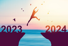 Silhouette Man Jumping Between Cliff With Number 2023 To 2024 And Birds Flying At Tropical Sunset Beach. Freedom Challenge And Travel Adventure Holiday Concept.