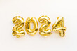 Golden foil balloons in form of numbers 2024 on white, New year card celebration, Gold air balloons, Holiday party decoration greeting card, top view