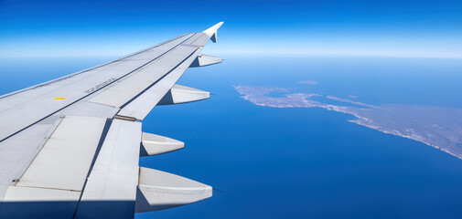Wall Mural - Plane flying over Greece. Greek island and blue Aegean sea water view out of airplane window.