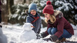 © BONI - Madre agachada e hijo de pie caucásicos y vestidos con ropa de invierno y gorros jugando con un muñeco de nieve un día nevado en familia