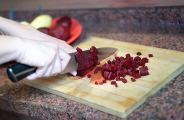 Wall Mural - Woman housewife cutting beets into cubes for salad closeup. Healthy food vegetarian cuisine concept