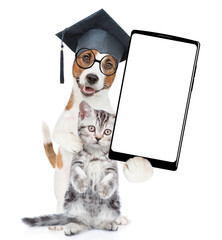 Poster - Smart Jack russell terrier puppy wearing graduation hat and eyeglasses hugs tabby kitten and shows big smartphone with white blank screen in it paw. isolated on white background