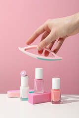 Tools for nail art and female hand on pink background