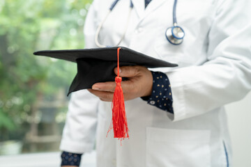 Wall Mural - Asian doctor study learn with graduation gap hat in hospital ward, clever bright genius education medicine concept.