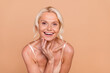 Photo of positive lovely retired lady toothy smile dressed stylish bra enjoying ideal skin serum cream isolated on beige color background