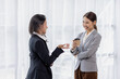© David - Happy two Asian women standing in suit talking together in the office or workplace,