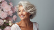 Confident elderly senior model with grey hair and makeup, mature happy smiling female lady with flowers in close-up portrait