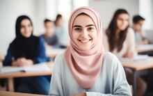 Happy Smiling Girl In Hijab In The Classroom With Students.Arab Woman Sitting At The Desk